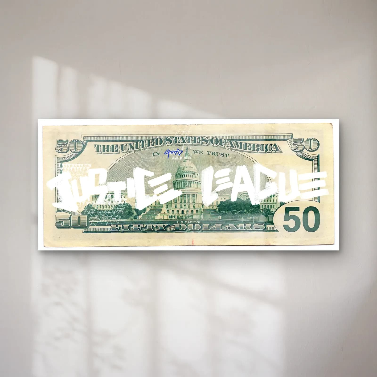 Justice League 50 Dolar cam tablo — 50 dolar banknotu üzerinde beyaz grafiti Justice League yazısı