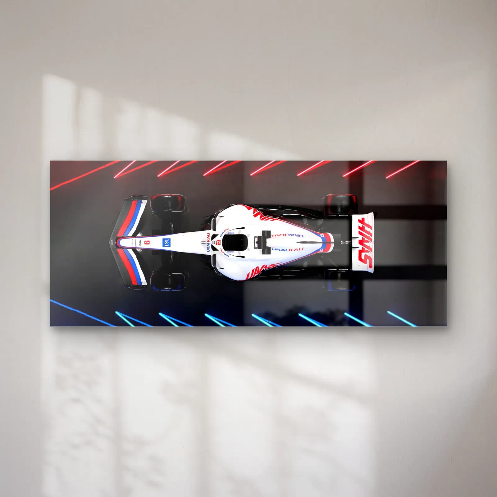 Neon Pistte Haas F1 cam tablo — Neon çizgili koyu zeminde yukarıdan görülen beyaz kırmızı Haas F1 aracı