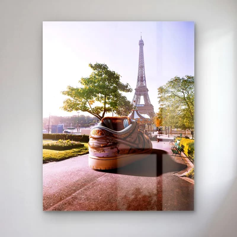 Paris'te Dev Sneaker cam tablo — Eyfel Kulesi önünde ağaçlı yolda duran dev kahverengi sneaker sürreal görseli
