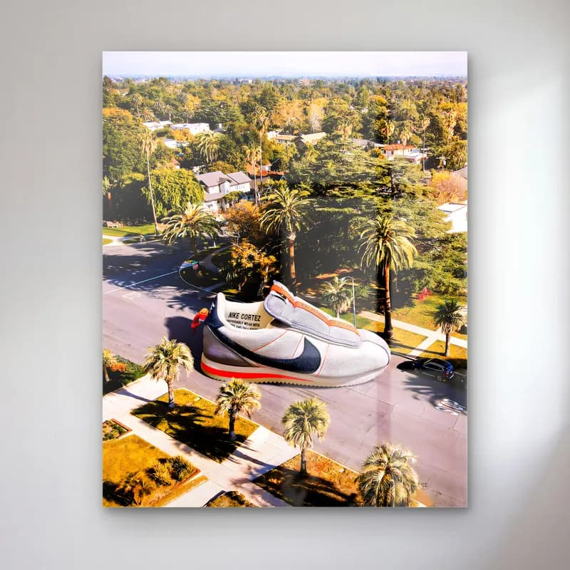 Palmiyeli Sokakta Dev Nike Cortez cam tablo — Palmiye ağaçlı caddede kuşbakışı görülen dev beyaz mavi kırmızı Nike Cortez